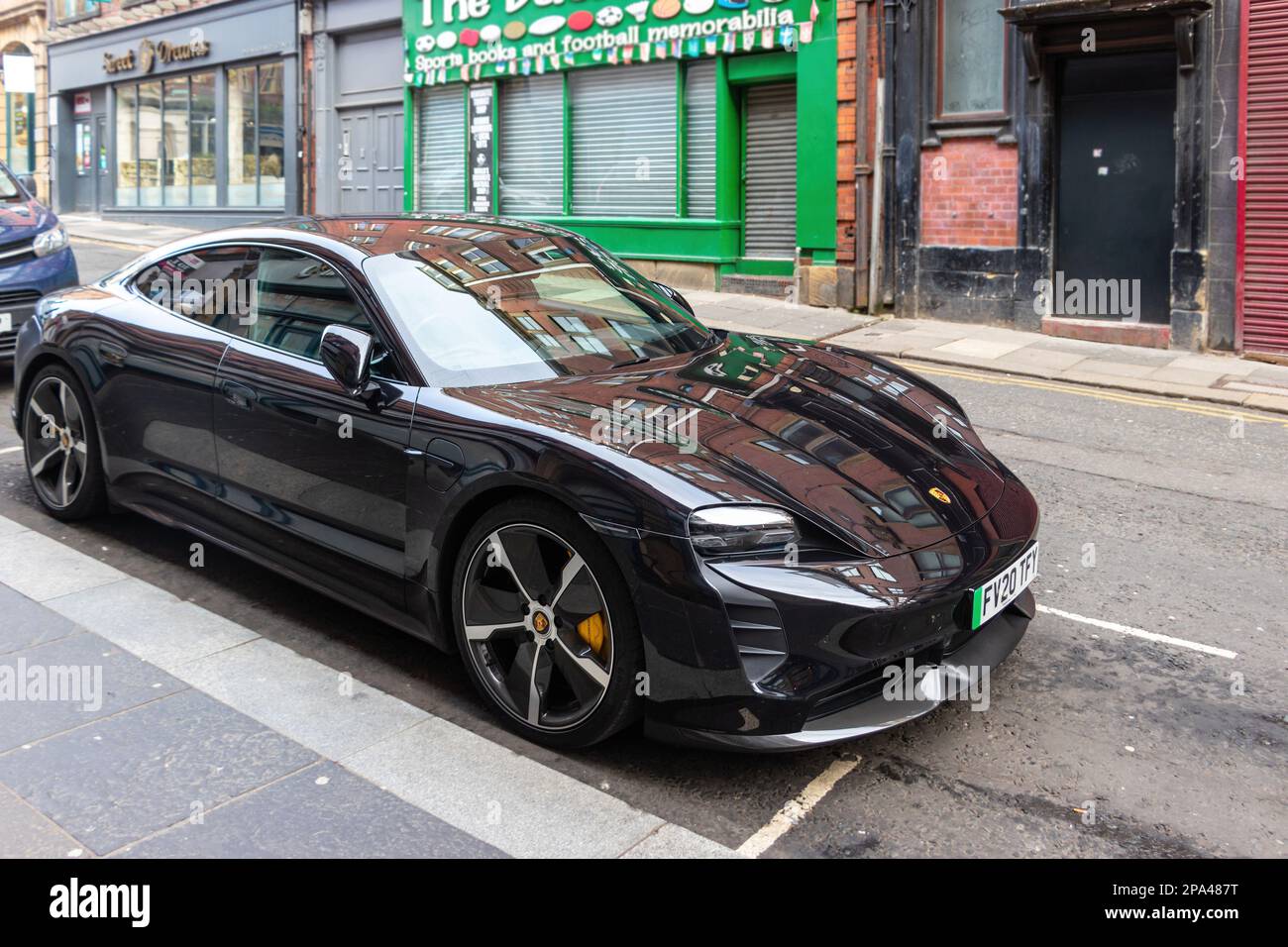 electric sports car black porsche Taycan Turbo S parked in street in