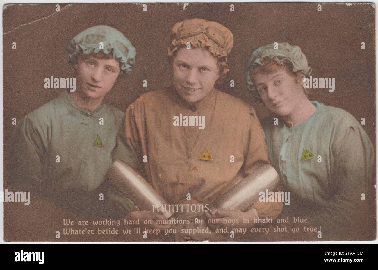 'Munitions. We are working hard on munitions for our boys in khaki and blue. Whate'er betide we'll keep you supplied, and may every shot go true': First World War postcard of three women munitions workers in working clothes (with mob caps). One woman is carrying two shells. All three are wearing triangular 'On War Service' badges Stock Photo