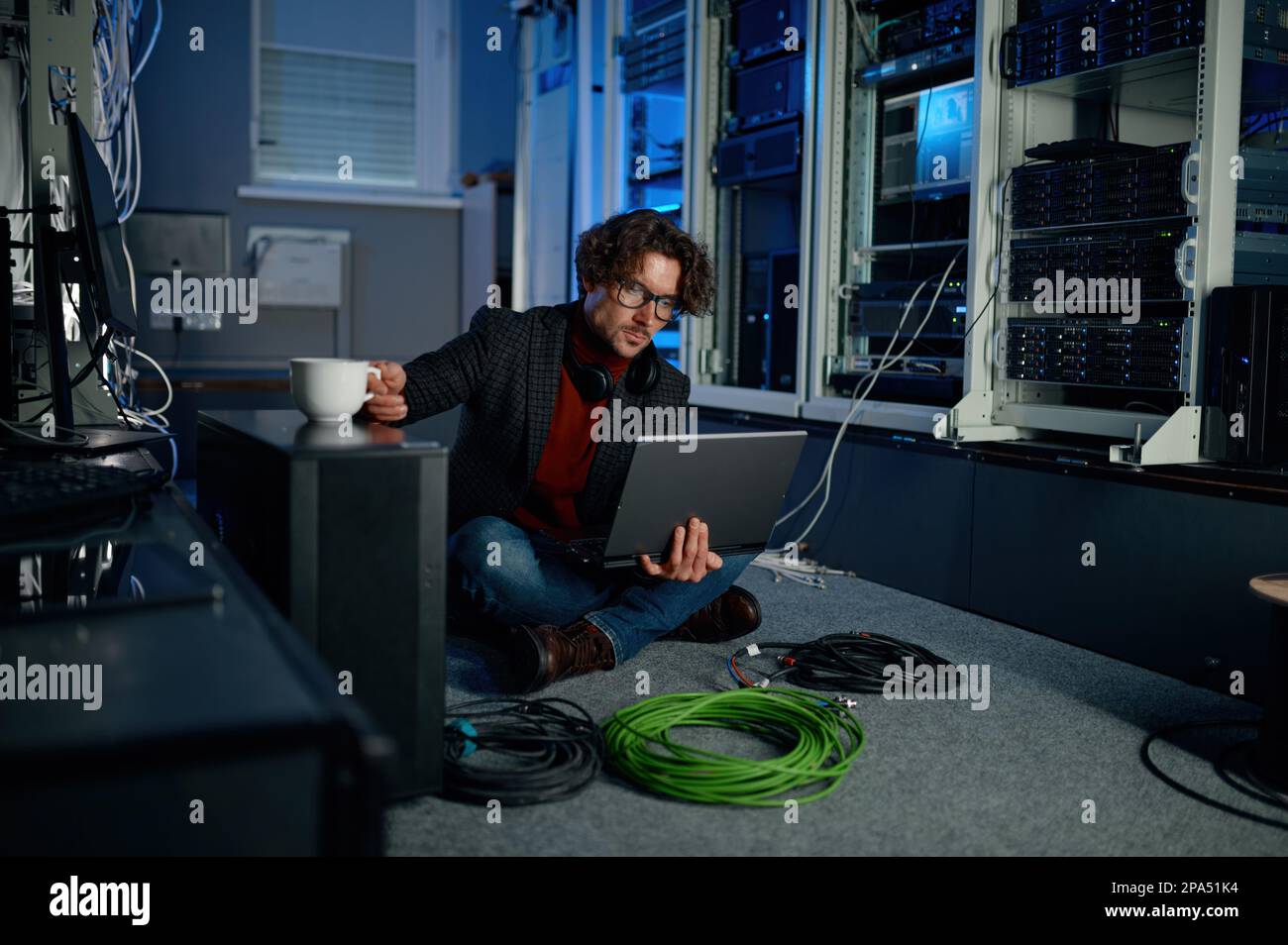 IT technician using laptop while working in data center Stock Photo