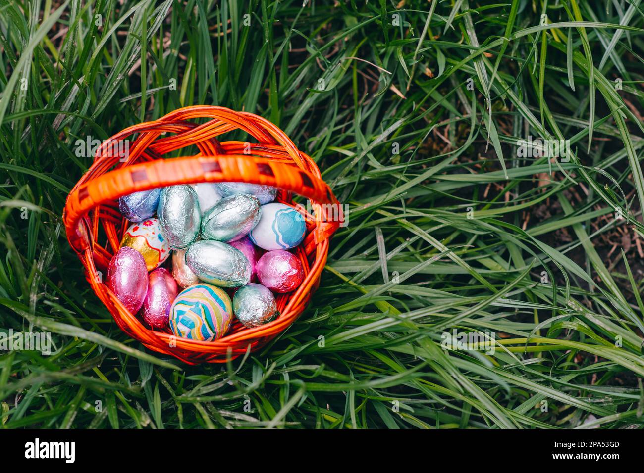 Chocolate Easter eggs in basket on green grass background nice Stock