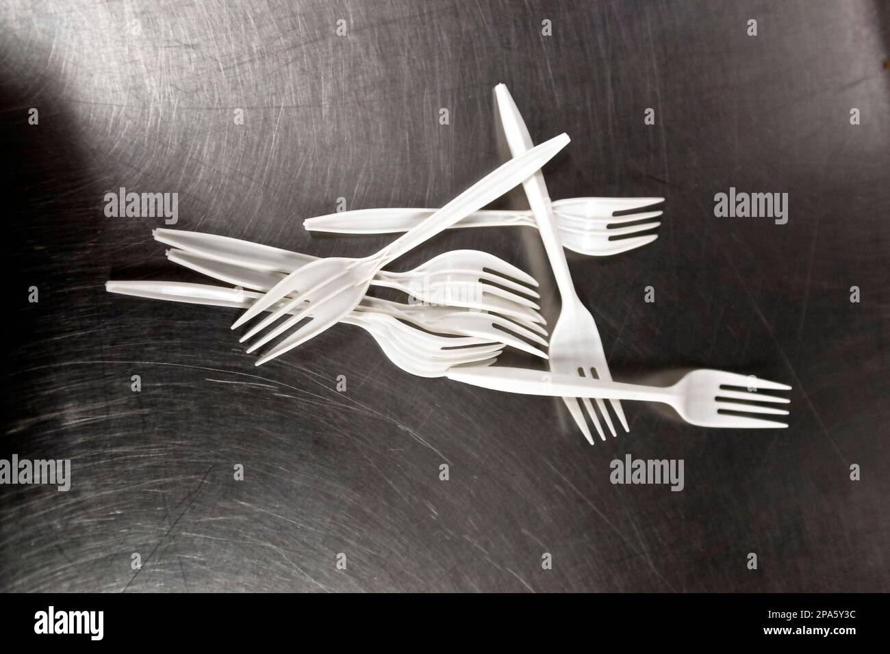 pattern of plastic forks on a scratched steel background Stock Photo