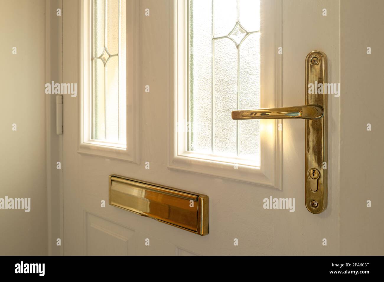 Shallow focus of a brass effect, new generation door lock and handle seen on a newly fitted, double glazed front door. Showing its double glazed, lead Stock Photo
