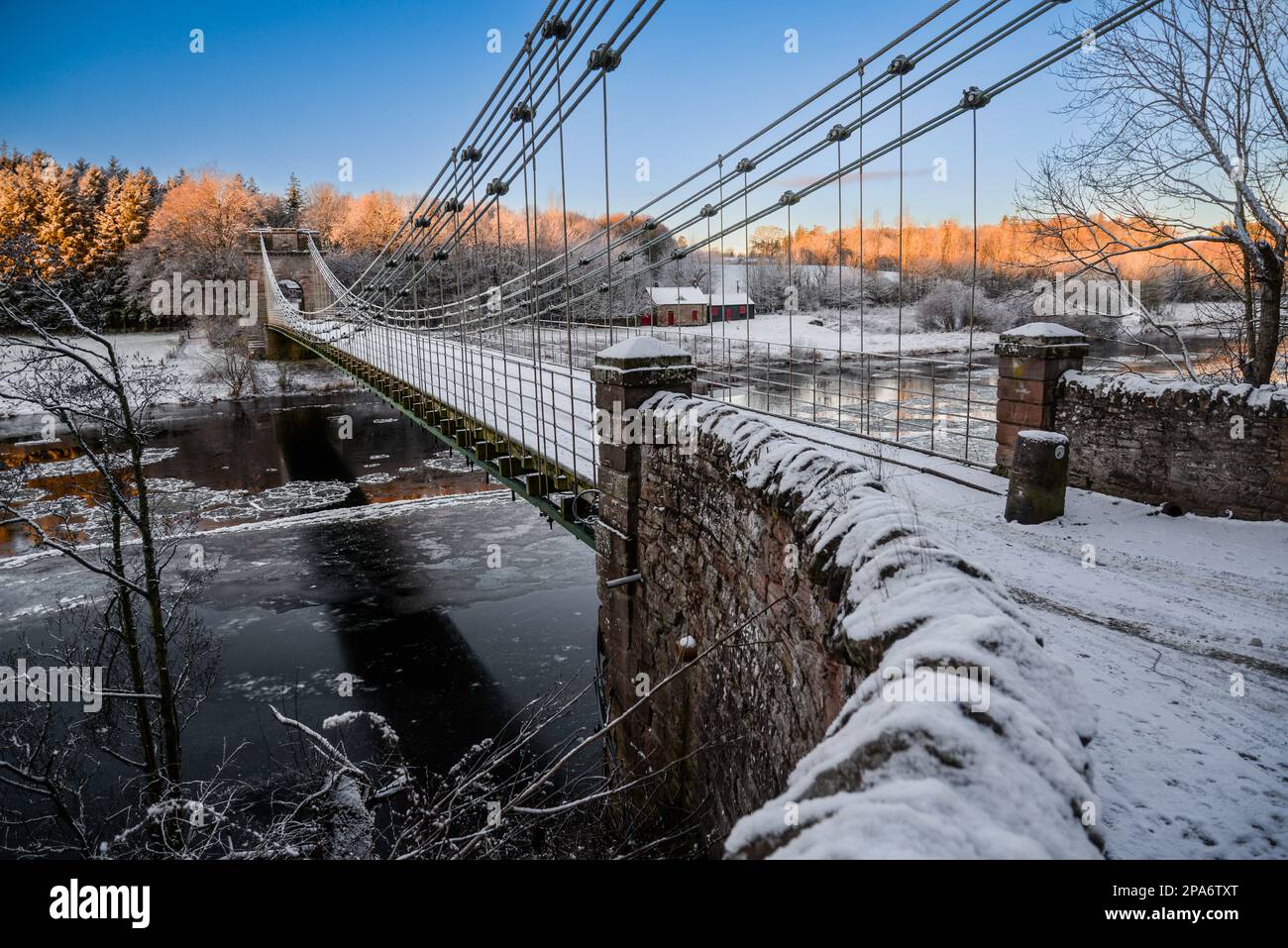 The Union Chain Bridge under a blanket of snow spanning the Tweed looking across the river towards the Scottish side of the border. Northumberland. UK Stock Photo