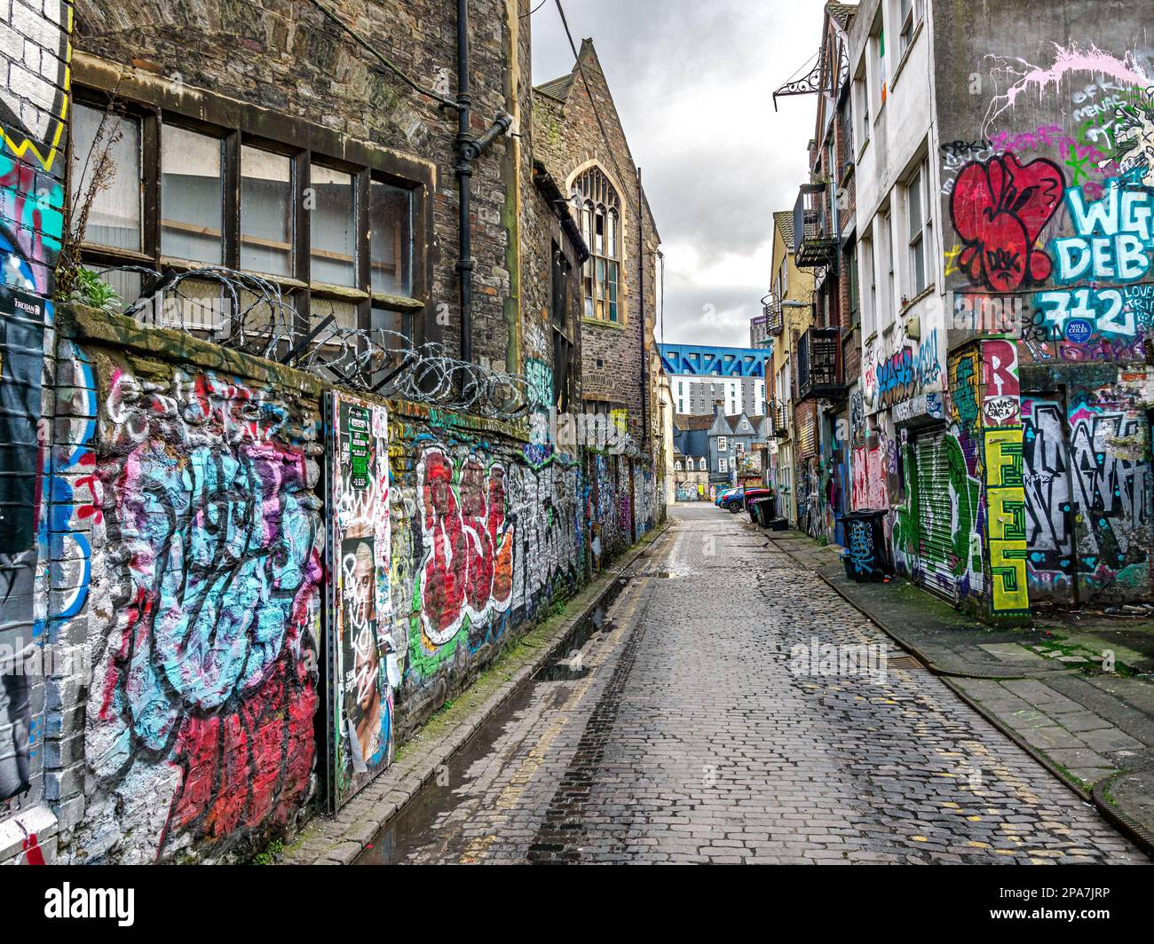Graffiti covered walls of a narrow alley in the Stokes Croft area close to the city centre of Bristol UK Stock Photo