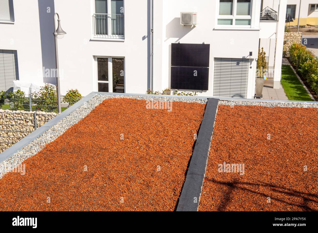 Flat roof with pebbles and red decorative stones, on which planting is
