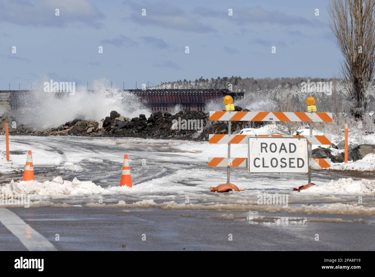 A road block detours motorists along Lakeshore Boulevard as waves crash