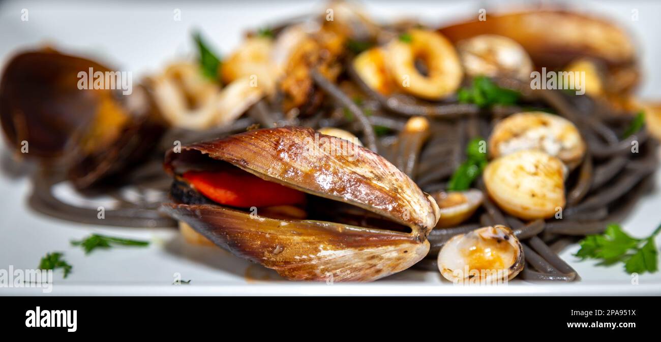 Black spaghetti with sepia squid ink with seafood, clams and shells ...