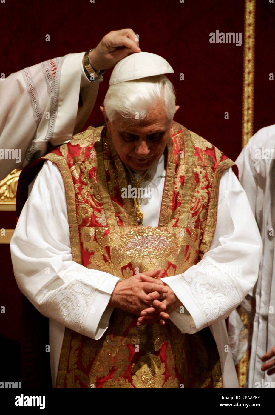 Pope Benedict XVI has his cap placed back on his head after praying