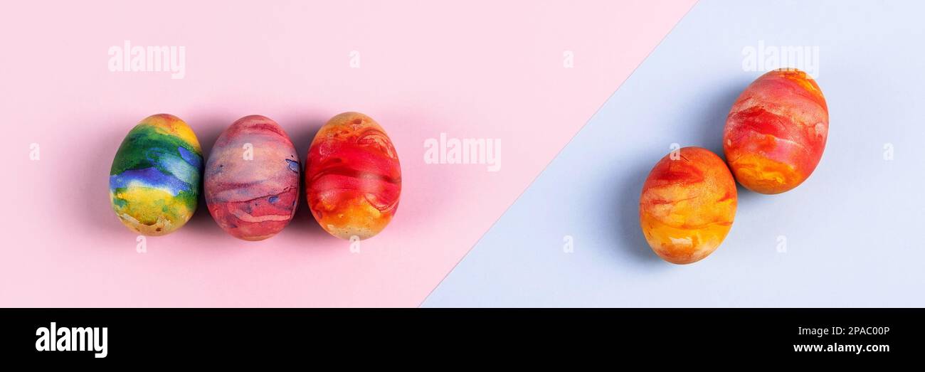 Painted Easter eggs in red yellow and orange on a blue and pink background with a place for text. Happy Easter concept. Greeting card. Banner Stock Photo