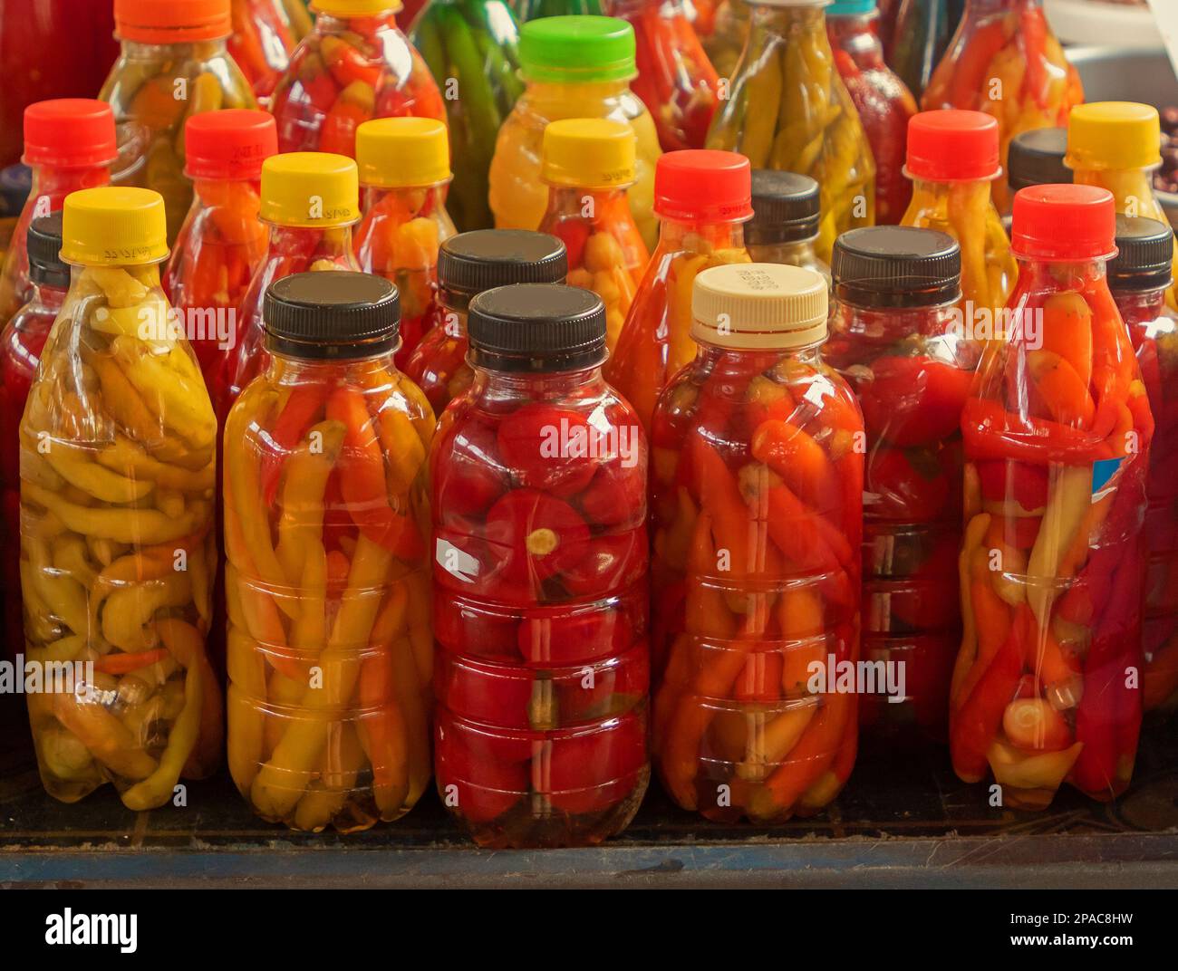 Preserved organic pickled vegetables stored in plastic bottles and glass jars sold on market stall outdoors Stock Photo
