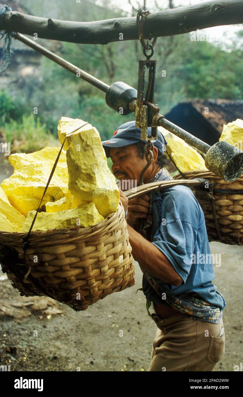 Sulphur mine labourer tallies his load after descending from Ijen Crater, East Java, Indonesia Stock Photo