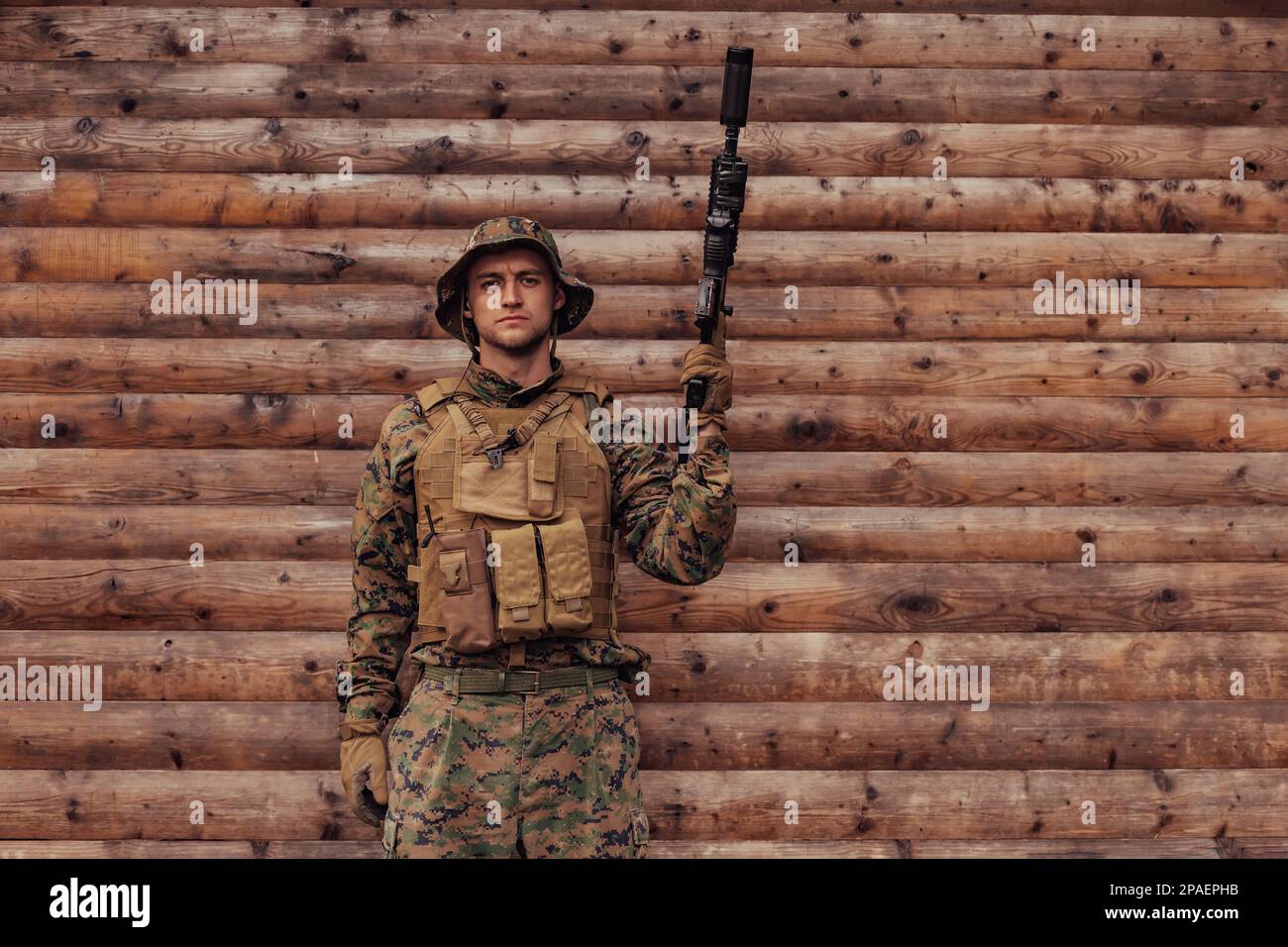 A soldier in uniform with a rifle in his hand is standing in front of a ...