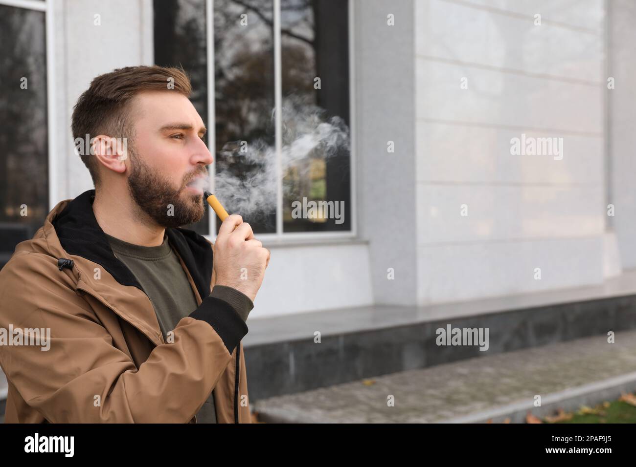 Handsome young man using disposable electronic cigarette outdoors Stock Photo