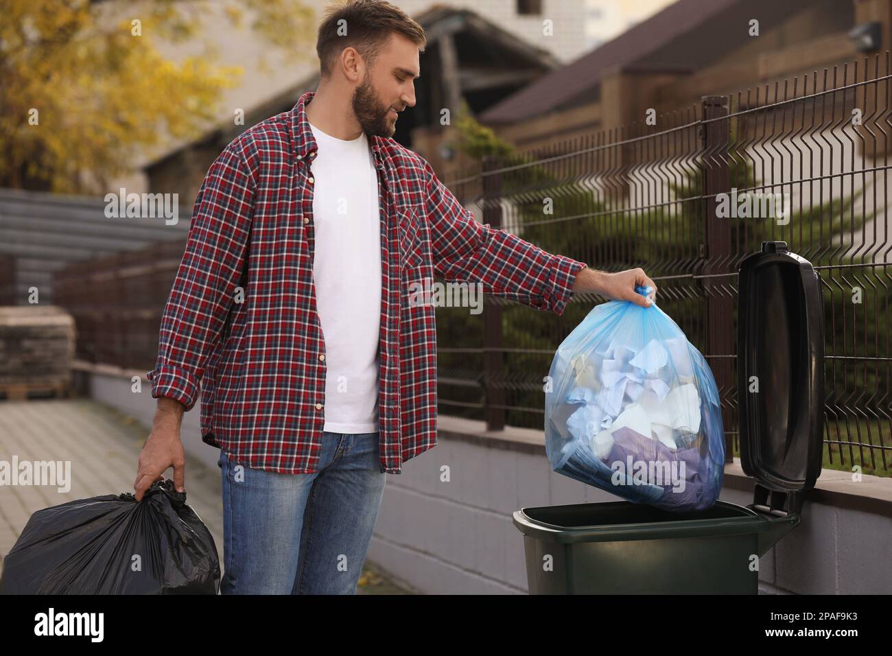 Man putting garbage bag into recycling bin outdoors Stock Photo Alamy