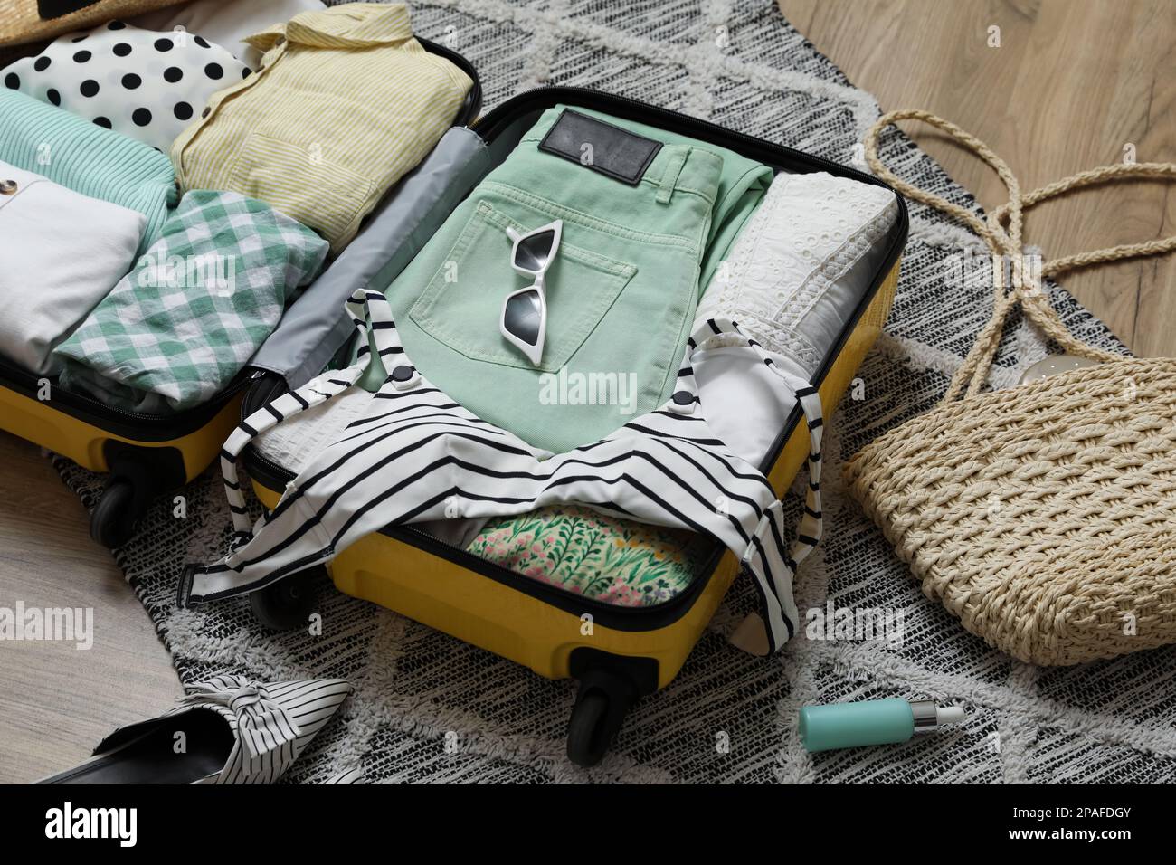 Open suitcase with summer clothes, accessories and shoes on floor Stock ...