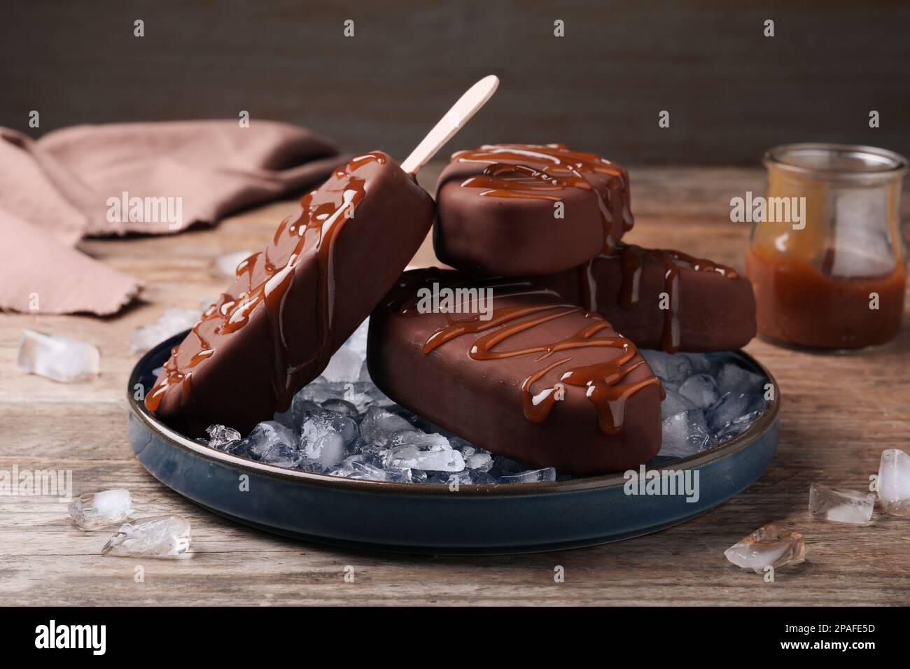 Delicious glazed ice cream bars and ice cubes on wooden table Stock Photo