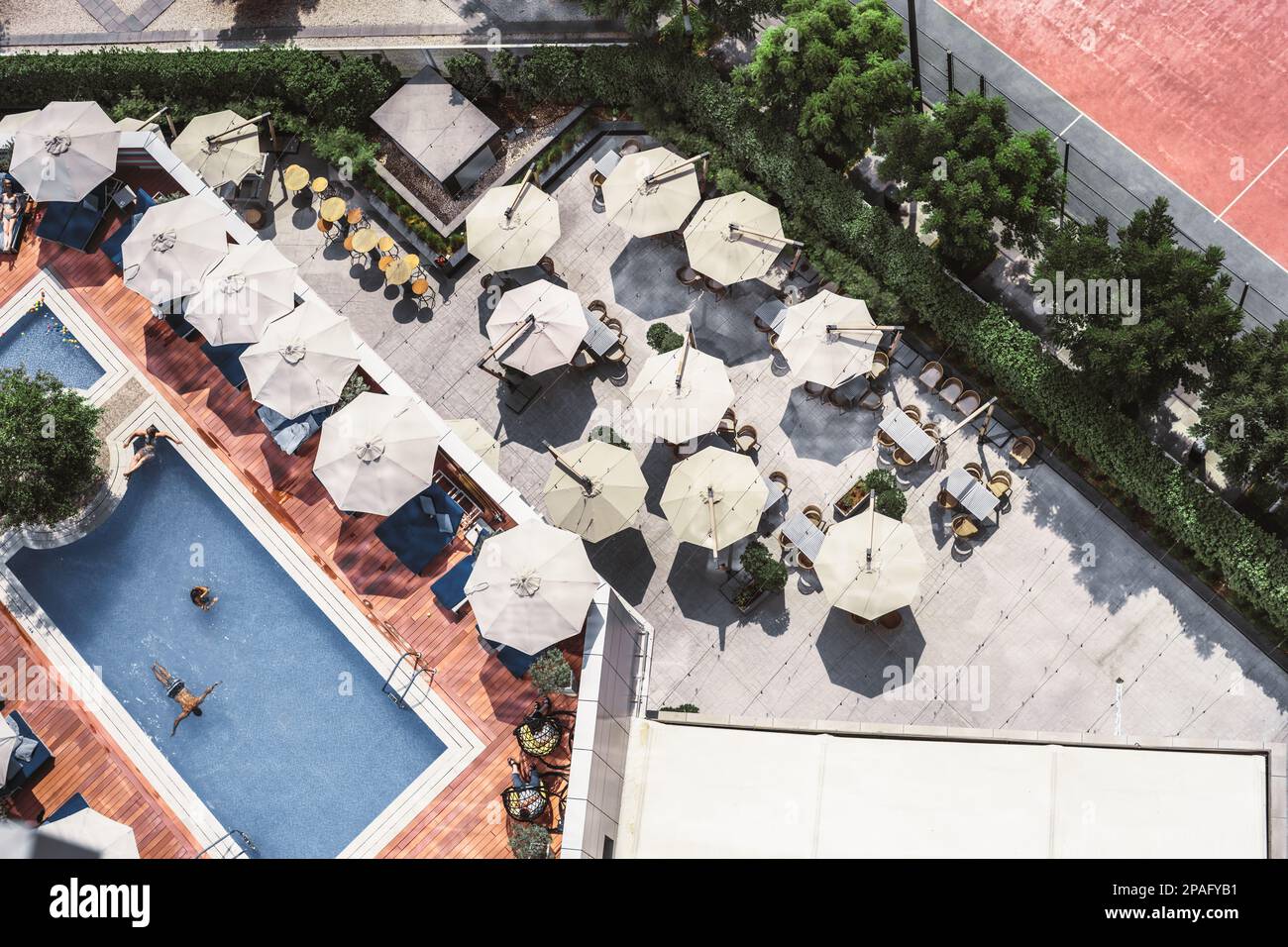 Shot from a drone, an outdoor bar with multiple open sunshades forms a nice landscape. Adjacent to the terrace lies a lush garden, while the other sid Stock Photo