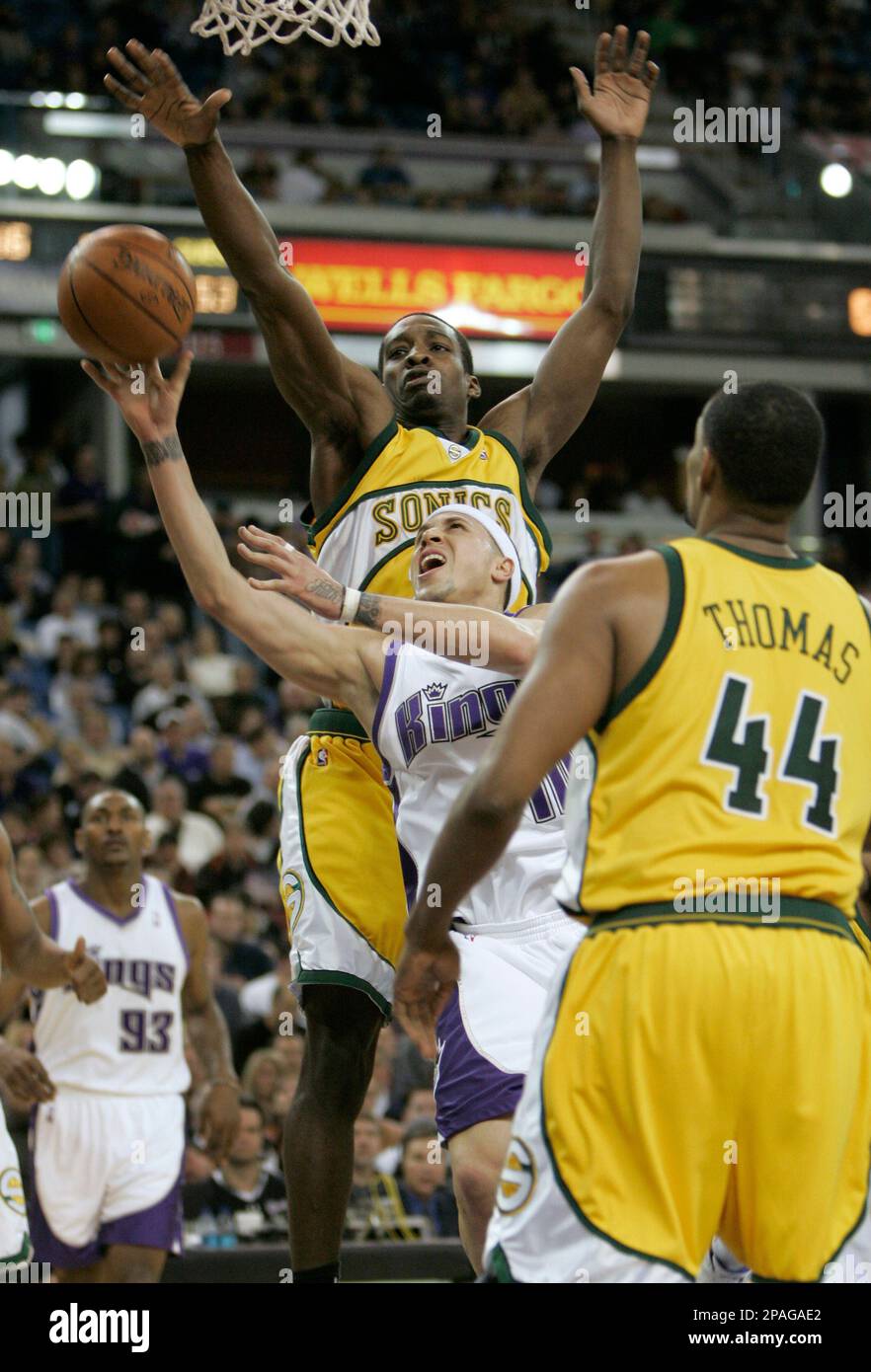 Sacramento Kings guard Mike Bibby, center, goes to the basket between  Seattle SuperSonics' Johan Petro, of France, left, and Kurt Thomas, right,  during the third quarter of an NBA basketball game in