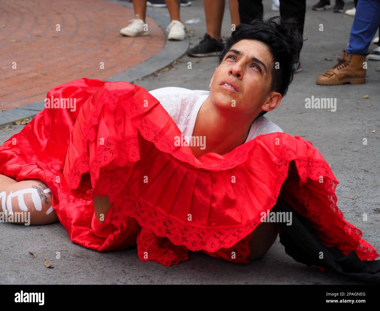 Woman dressed in red and white lying on the ground when hundreds of women  took to the streets to march asking for their rights, in the framework of  the activities for the