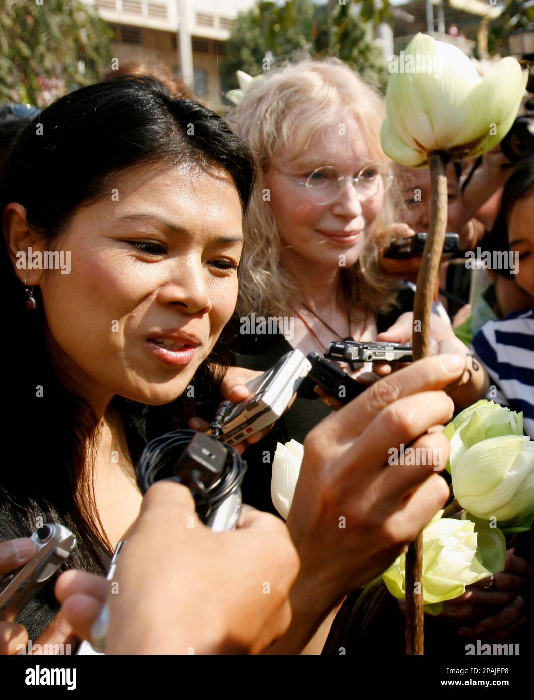 Theary Seng, left, Cambodian Executive Director of the Center for Social Development, left, and American actress Mia Farrow, right, give lotus flowers to police officers as authorities block their group outside Tuol Sleng genocide museum in Phnom Penh, Cambodia, Sunday, Jan. 20, 2008. Cambodian police blocked Farrow from holding a genocide memorial ceremony Sunday at a Khmer Rouge prison, at one point forcefully pushing her group away from a barricade. (AP Photo/Heng Sinith) Stock Photo