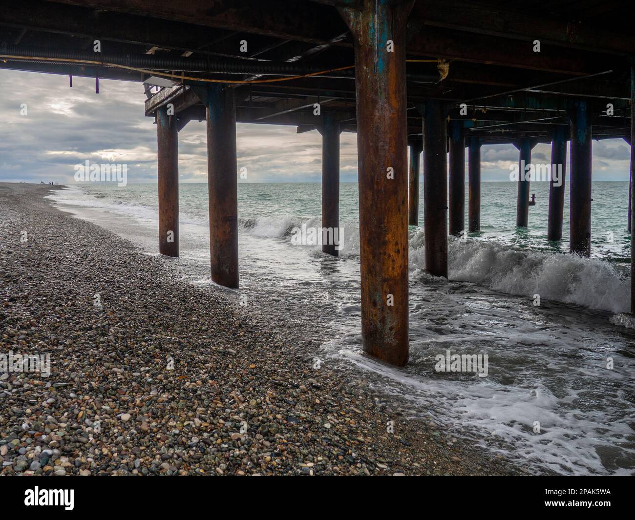 Metal pier on columns. Construction on the sea.Rusty pier. Resort place in  winter on a cloudy day Stock Photo - Alamy