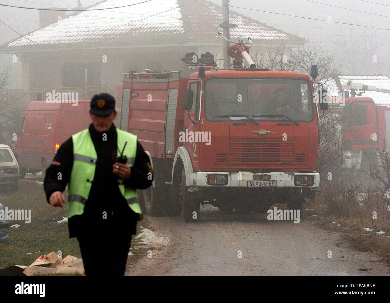 Police and firefighters are seen through a fog, near the site of a