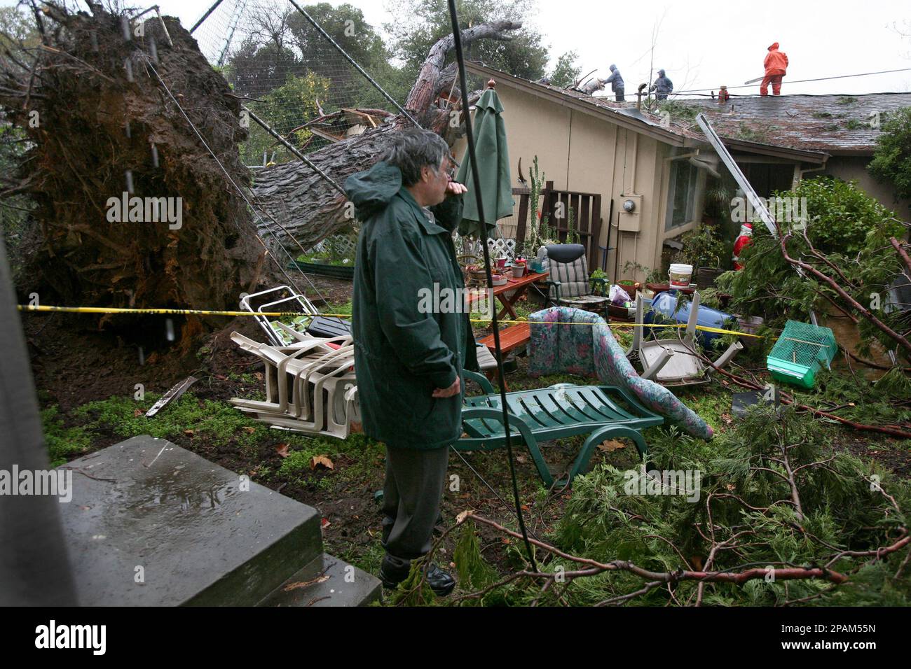 Richard Garcia looks over damage to his house after a large tree up