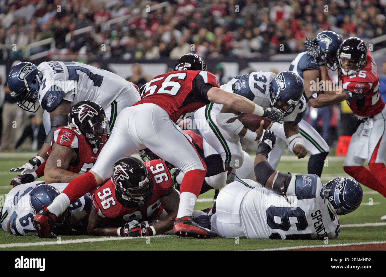 Seattle Seahawks running back Shaun Alexander (37) breaks through the line  for a touchdown as Atlanta Falcons linebacker Keith Brooking (56) closes in  during the first quarter of a football game Sunday ,