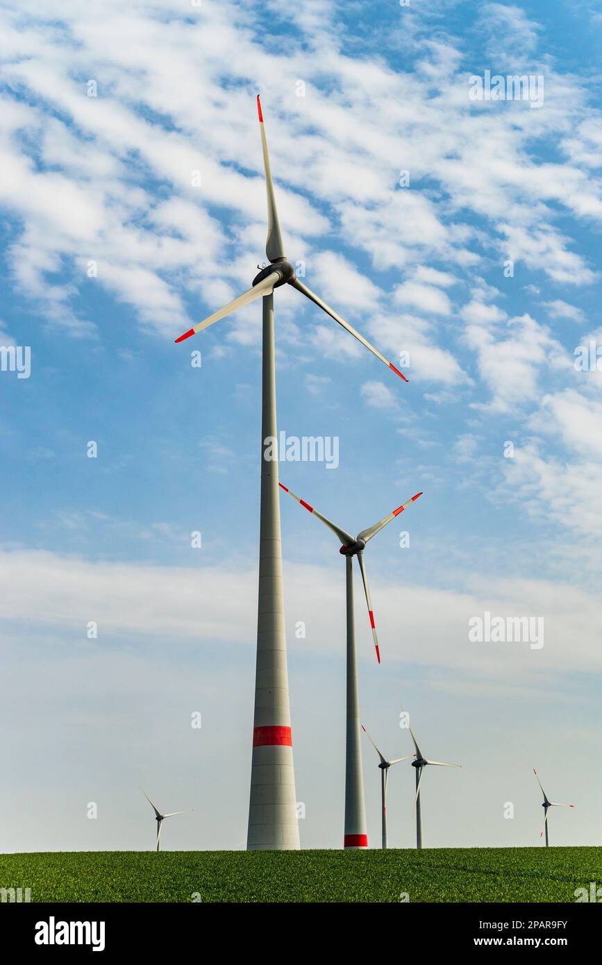 Group of wind turbines against a cloudy blue sky in a rural landscape ...