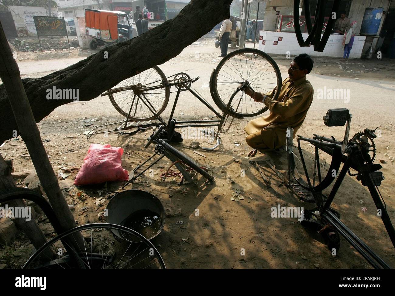 A Pakistani man operates a bicycle repair stall on a street corner in