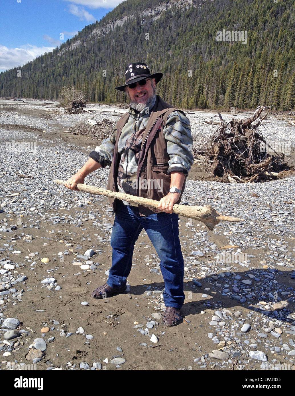 Elderly man with a black stetson on is acting aggression. He has a pointed stick in his hands. Stock Photo