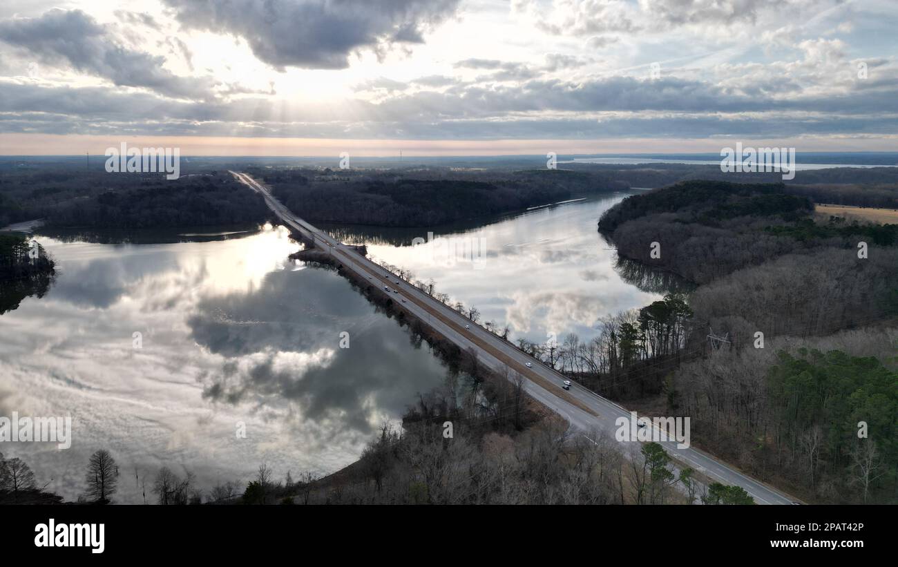 An aerial view of a long bridge stretching across the water with a vibrant sky in the background. Stock Photo