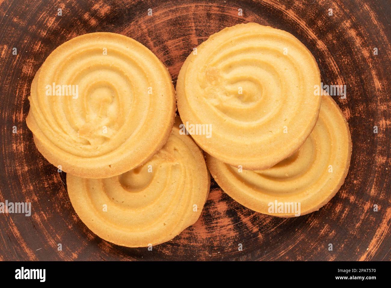 Four sweet cookies on a clay saucer, macro, top view. Stock Photo
