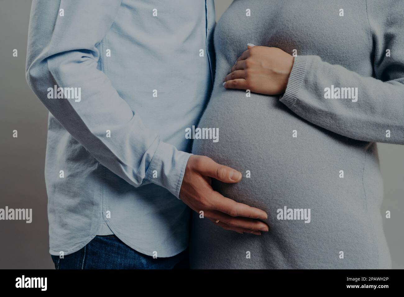 Cropped shot of unrecognizable woman and man expect baby. Pregnant wife pose with husband indoor. Future parents prepare for child birth Stock Photo