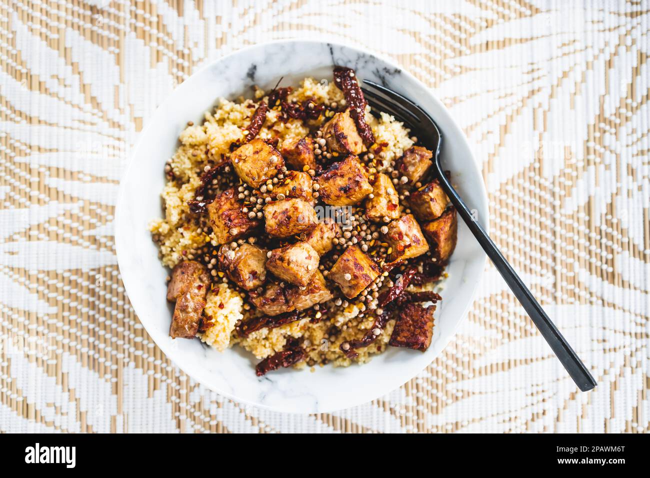 plant-based couscous with grilled tempeh cubes topped with chilli flkes and coiander seeds, healthy vegan food recipes Stock Photo