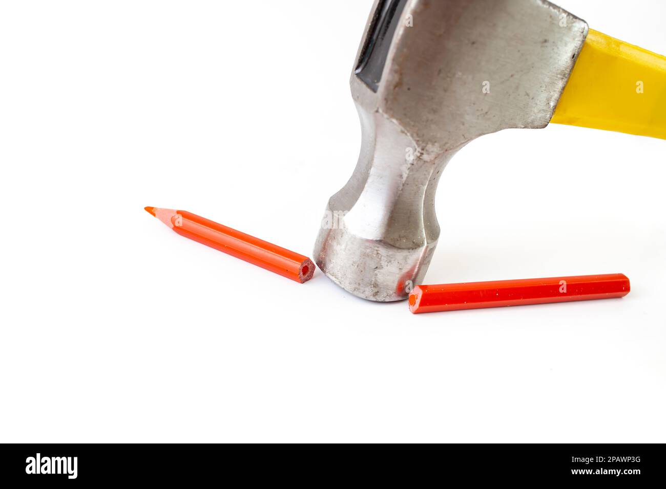 Hammer breaking a red crayon in two pieces, isolated on white background, soft focus close up. Stock Photo