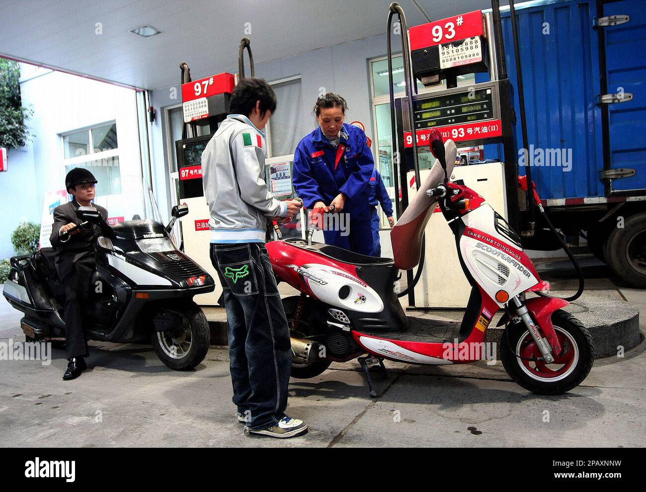 Moped owners line up to fill their tanks at a gas station Tuesday Oct