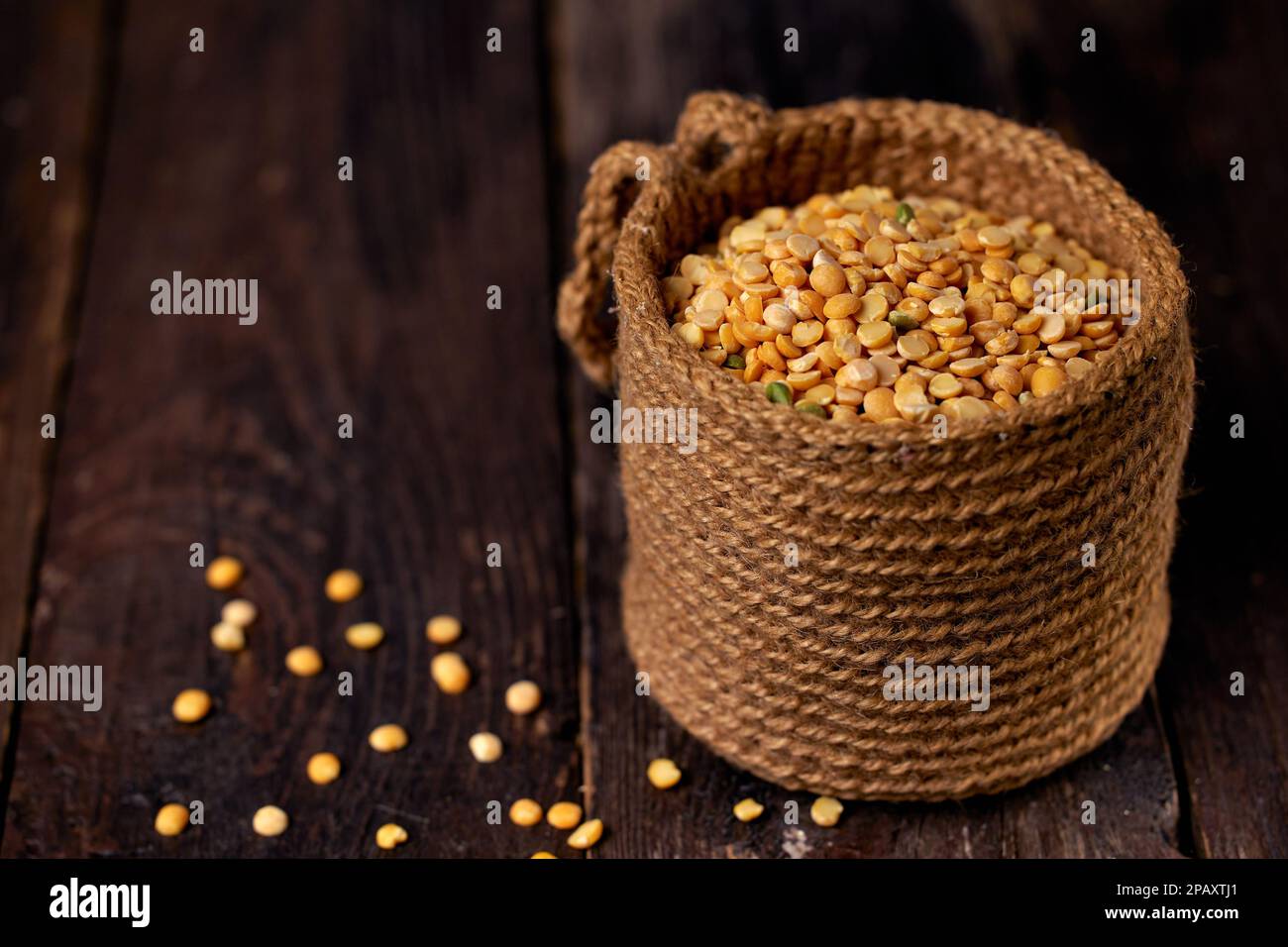 Dry yellow pea grains in a jute bag on a dark wooden table Stock Photo