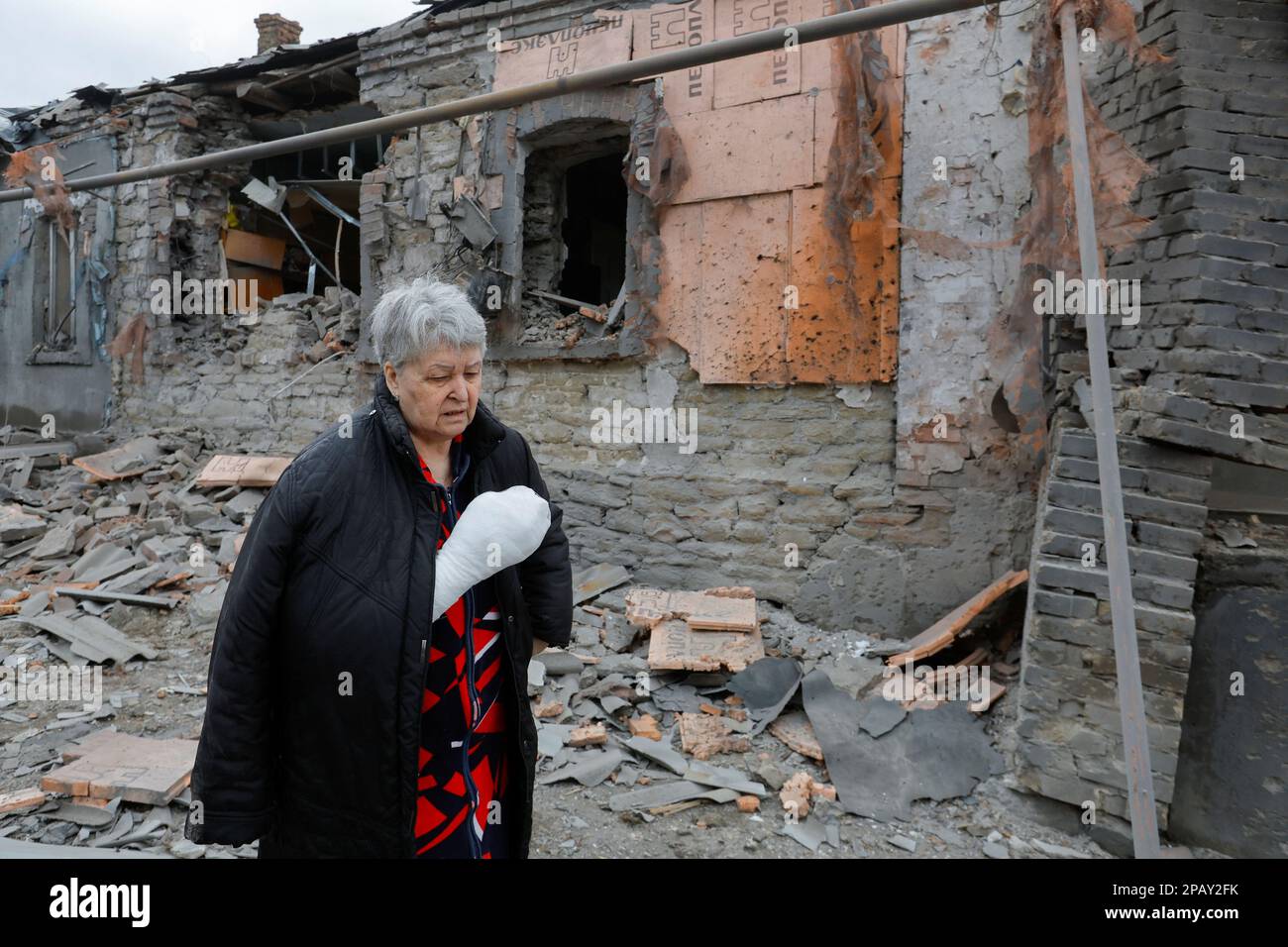 Local resident Svetlana Boiko, 66, who was injured in recent shelling, walks outside her destroyed house in the course of Russia-Ukraine conflict in Donetsk, Russian-controlled Ukraine, March 12, 2023. REUTERS/Alexander Ermochenko Stock Photo