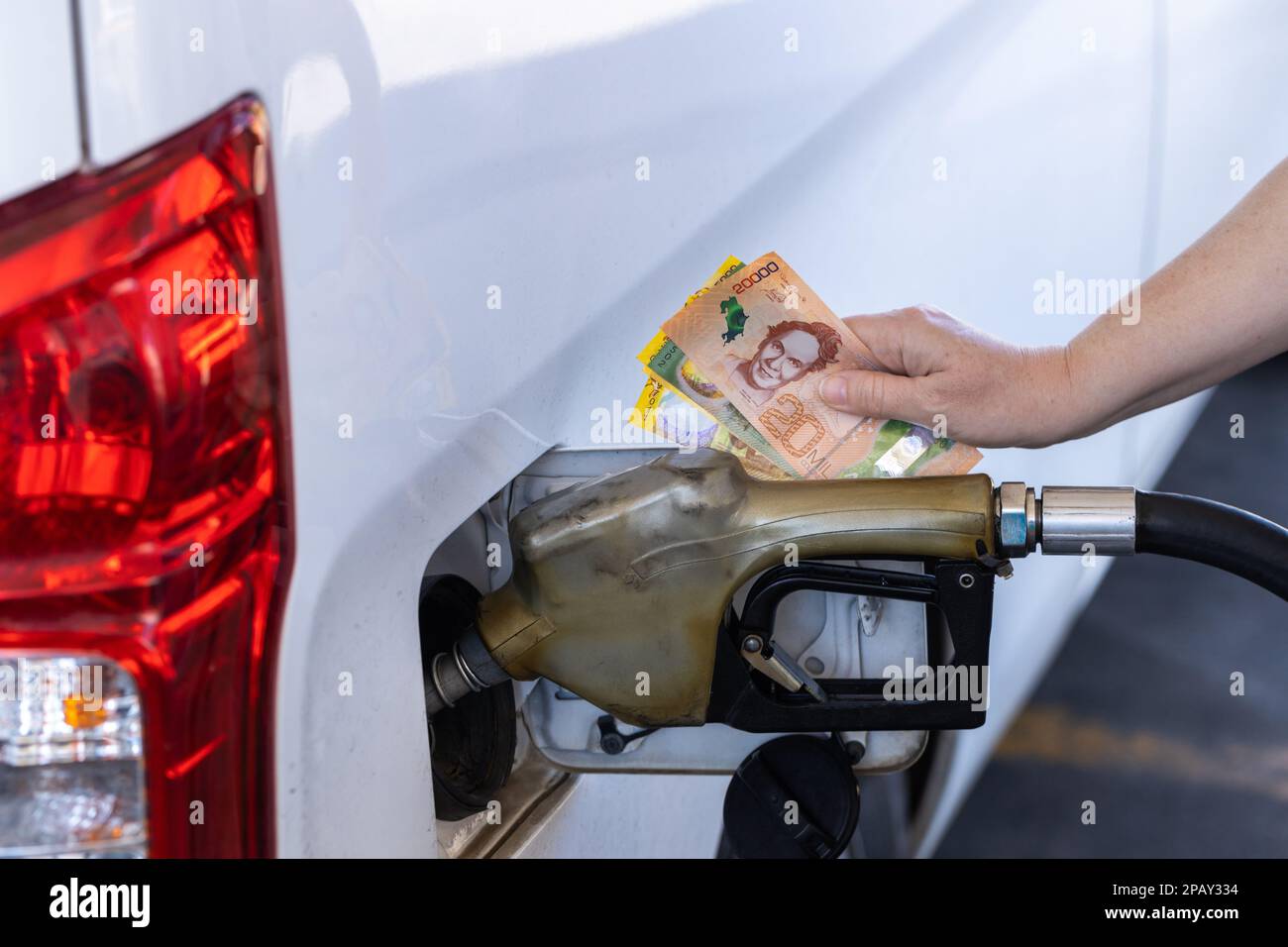Costa Rica, gas station, woman holding a handful of money by the car