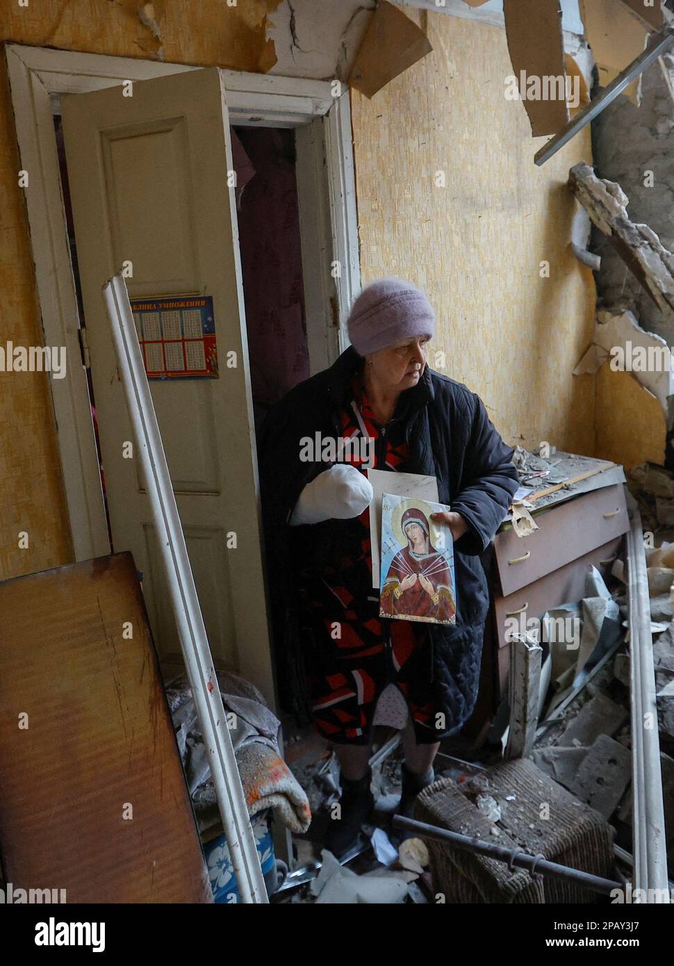 Local resident Svetlana Boiko, 66, who was injured in recent shelling, holds an icon while walking out of her destroyed house in the course of Russia-Ukraine conflict in Donetsk, Russian-controlled Ukraine, March 12, 2023. REUTERS/Alexander Ermochenko Stock Photo