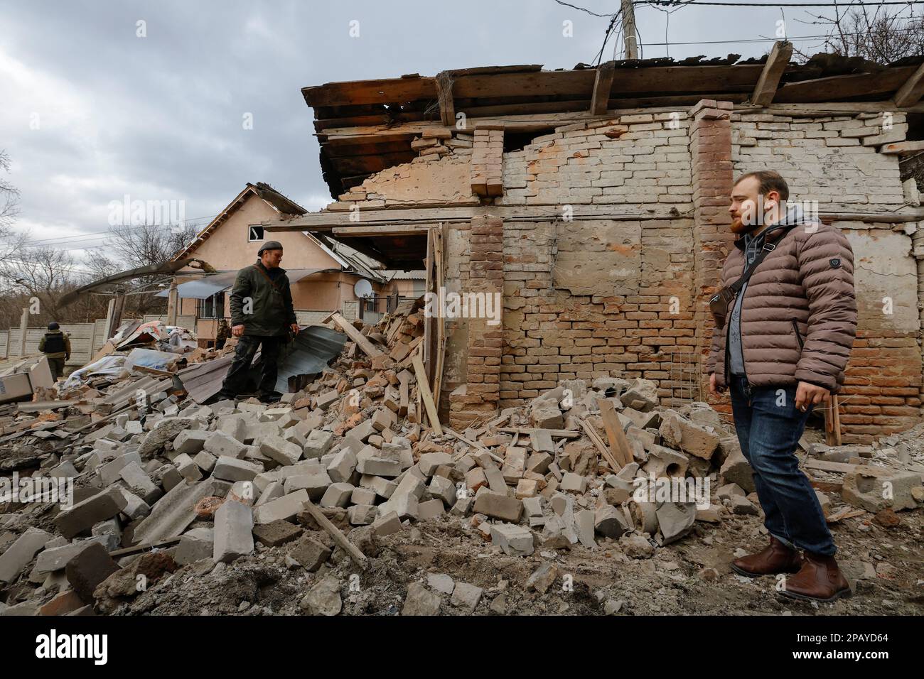 Men stand near buildings damaged in recent shelling in the course of Russia-Ukraine conflict in Donetsk, Russian-controlled Ukraine, March 12, 2023. REUTERS/Alexander Ermochenko Stock Photo