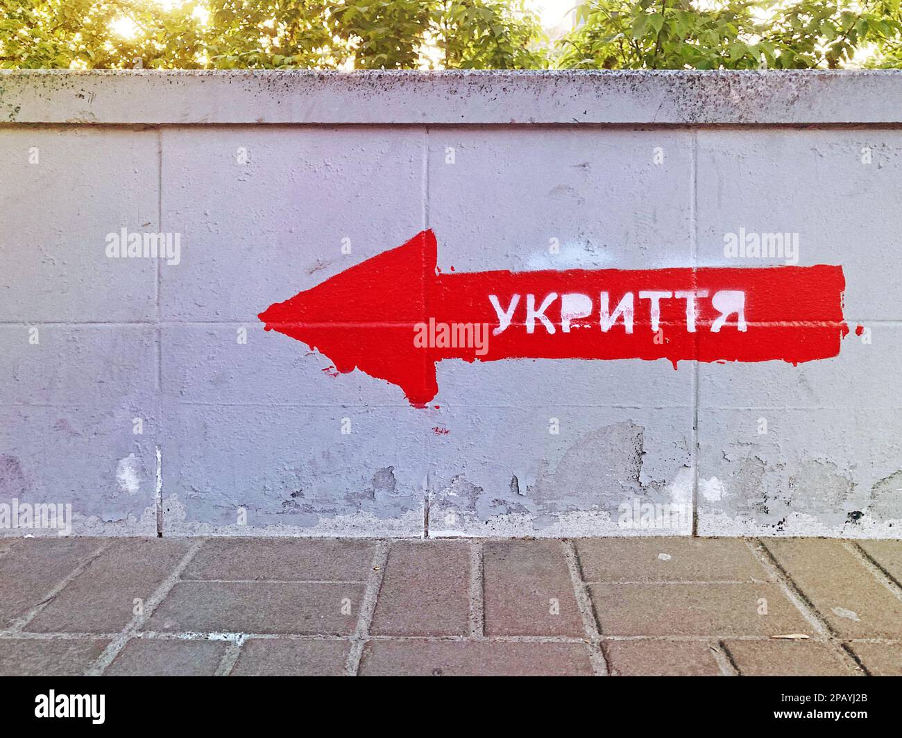 Bomb shelter sign on the building wall. The inscription in Ukrainian SHELTER on the wall. Signpost direction to the bomb shelter in Ukrainian. KYIV, U Stock Photo