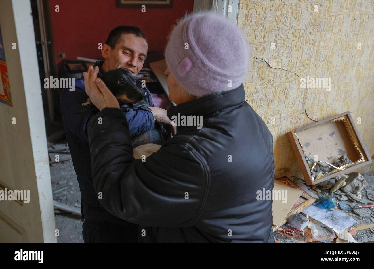 Local resident Svetlana Boiko, 66, strokes her dog carried by a neighbour inside her house destroyed in recent shelling in the course of Russia-Ukraine conflict in Donetsk, Russian-controlled Ukraine, March 12, 2023. REUTERS/Alexander Ermochenko Stock Photo