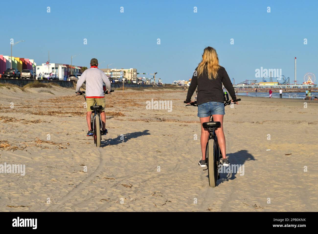Galveston, Texas, USA - February 2023: Two people cycling on the beach on electric bikes Stock Photo