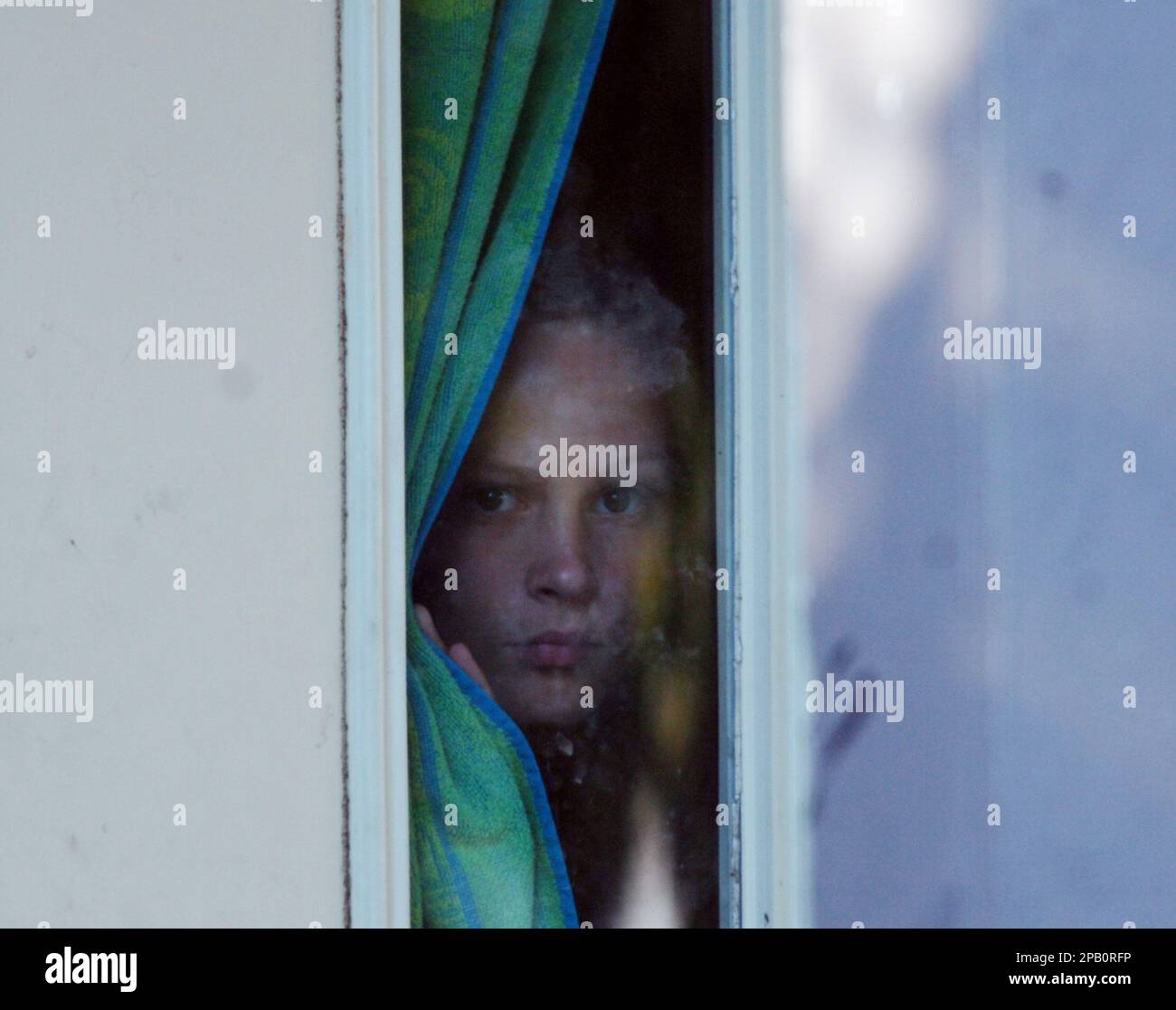 Nicole Coon, the sister of Asa Coon, peers through a window while at home Thursday, October 11, 2007 on West 43rd Street in Cleveland. Asa H. Coon, 14,opened fire Wednesday at SuccessTech Academy wounding two students and two teachers. (AP Photo/Dave Richard) Stock Photo