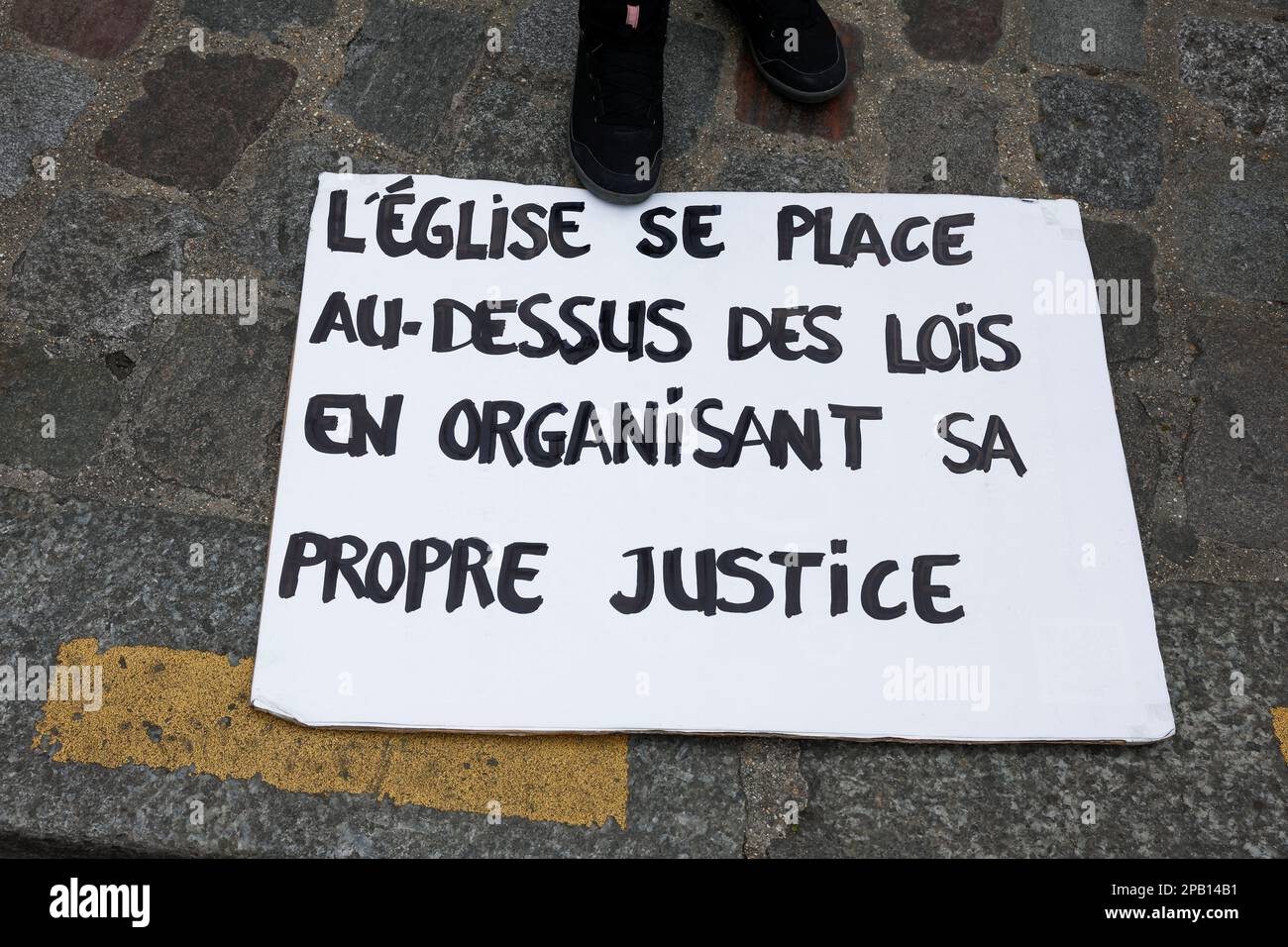 A person participates in a gathering organised by Tous Ensemble and Be Brave France associations to support the victims of sexual abuse by the French Catholic Church, outside the Sacre-Coeur Basilica at the Butte Montmartre in Paris, France, March 12, 2023. The placard reads 'The church places itself above the law by organising its own justice'. REUTERS/Benoit Tessier Stock Photo