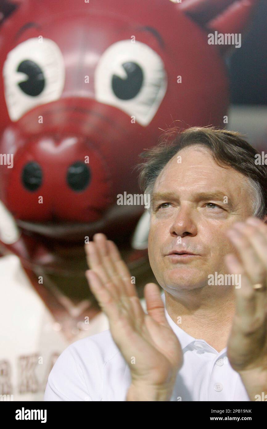 Arkansas coach Houston Nutt sings with his team on the field near the