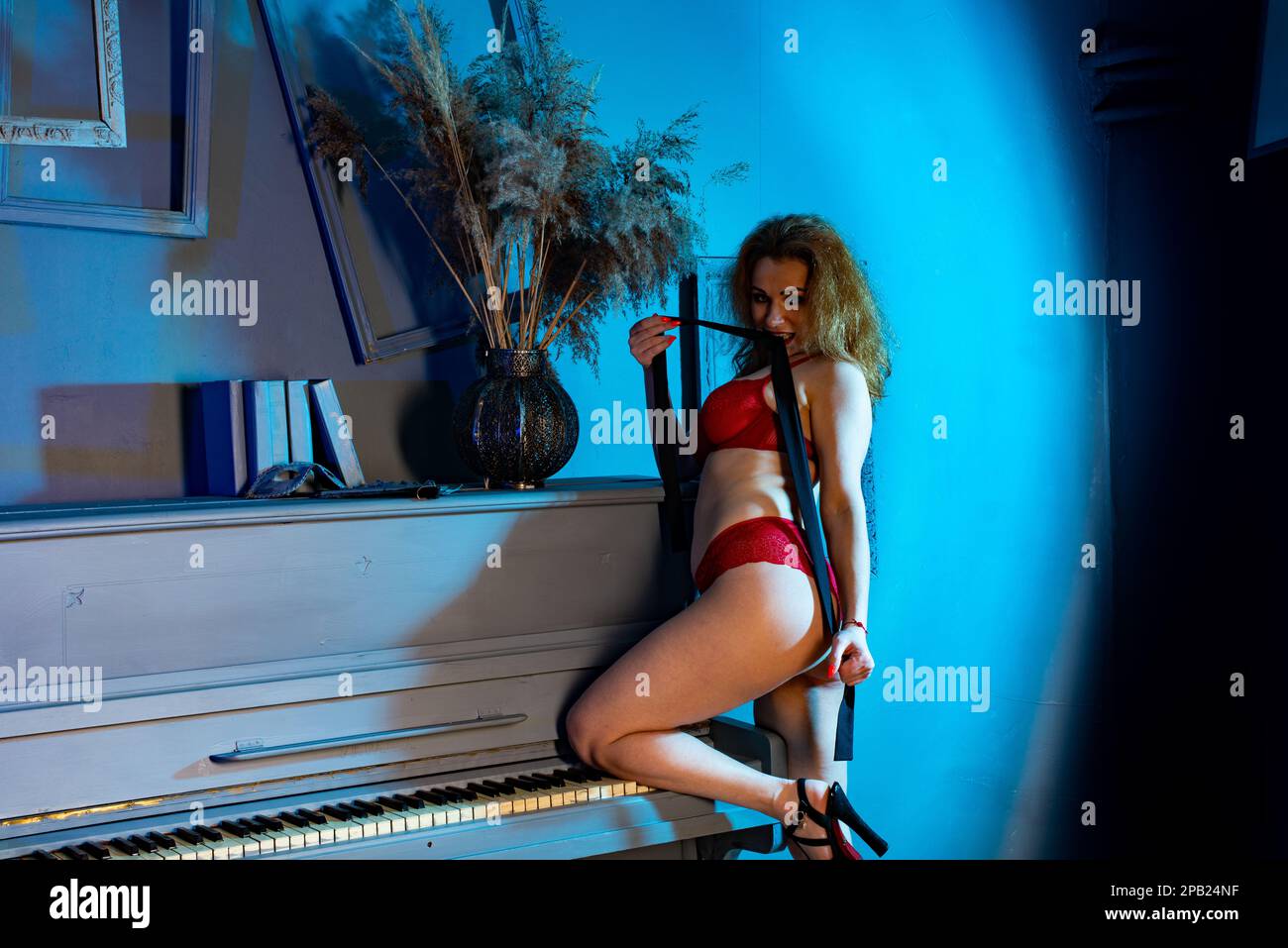 Beautiful young girl in sexy red lingerie on a piano. Woman with fashion  bracelet. Fashion studio shot Stock Photo - Alamy