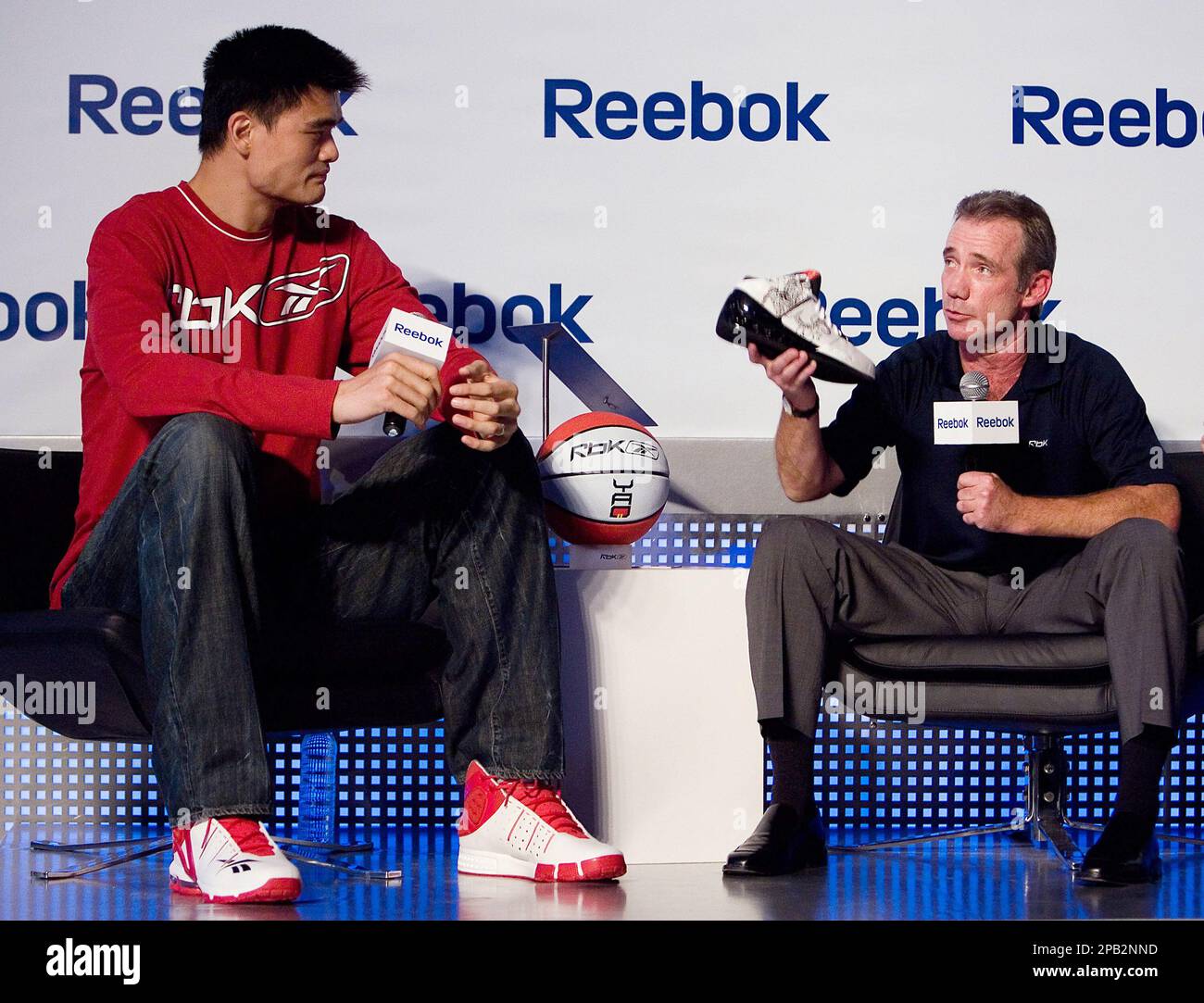 Reebok President and CEO, Paul Harrington, right, shows its latest  basketball shoes model while NBA Houston Rockets' star Yao Ming looks on  during a news conference in Beijing, China, Tuesday, Sept. 25,